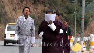 Bhutanese boys wearing the traditional attire Gho walk on the streets of Thimphu [upl. by Berthold]