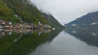 Clouds and fog are reflecting in the still waters of Lake Hallstatt with the town nestled on the [upl. by Dorella870]