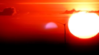 000276 A WIND TURBINE SLOWLY ROTATES IN FRONT OF THE RISING SUN AND THEN STOPS LIKE THE SUN [upl. by Derian860]